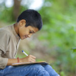 child writing in notebook